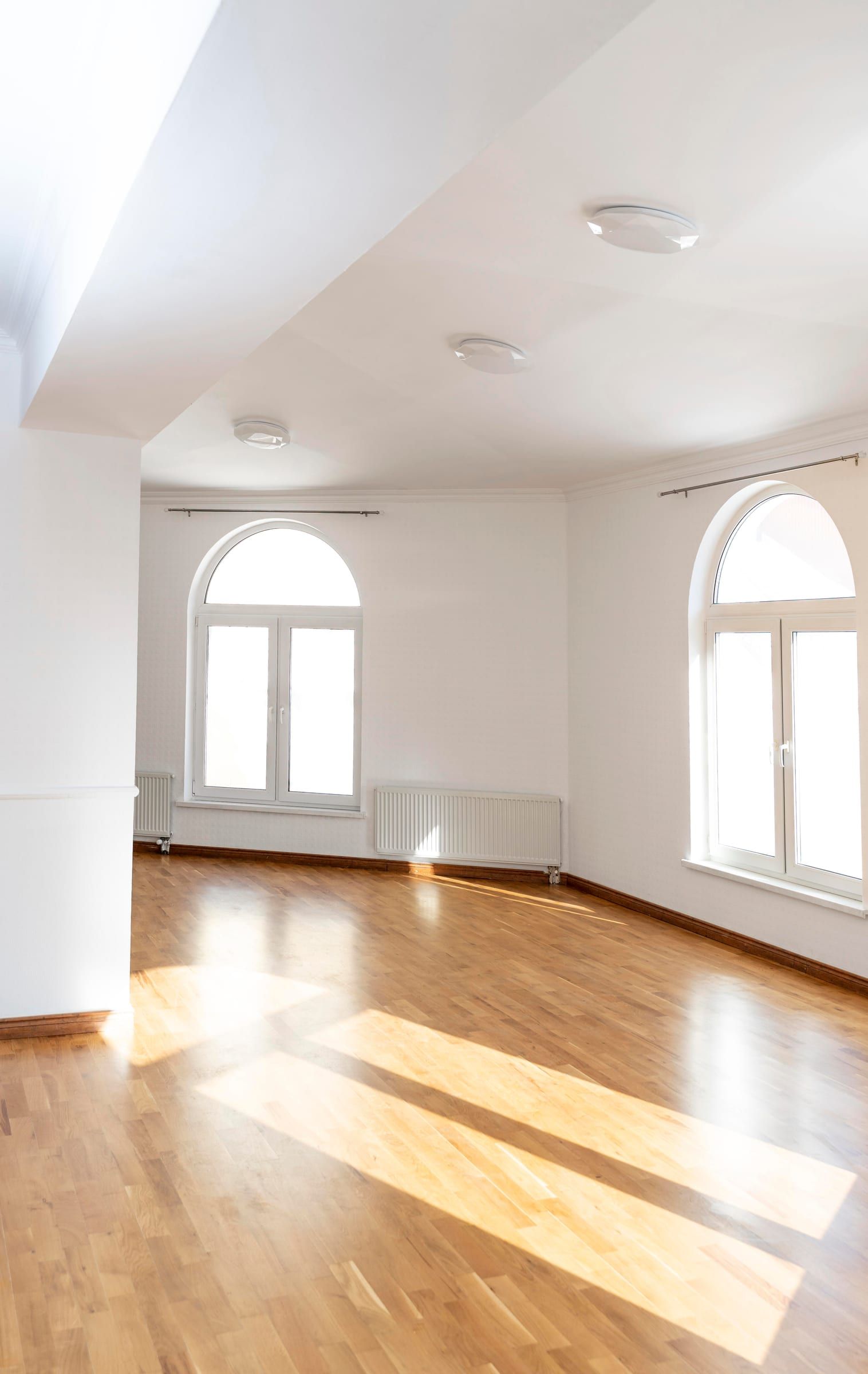 Leere, helle Altbauwohnung mit Parkett und Rundbogenfenstern
