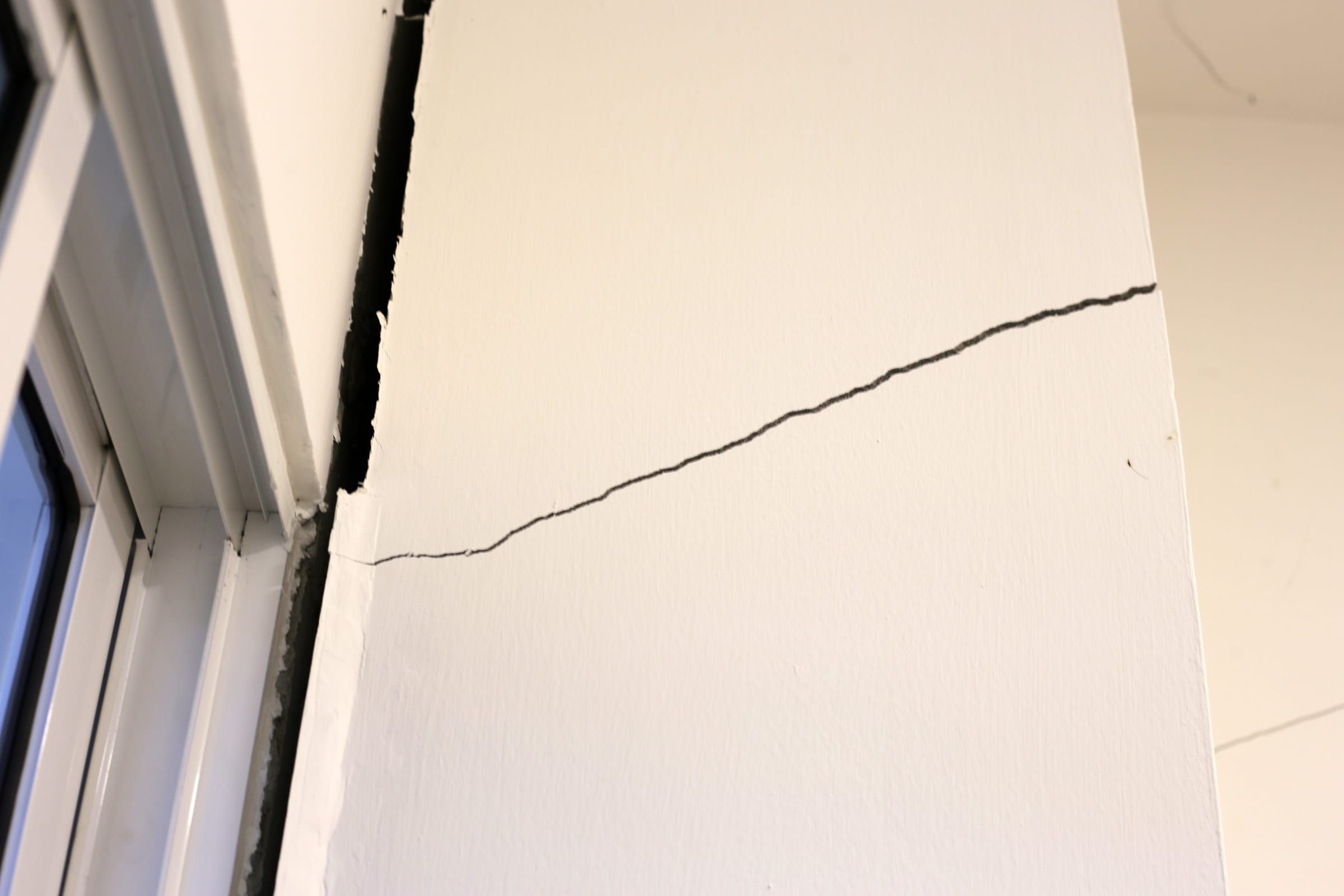 Riss, der von einer Fensterecke in die Wand läuft
